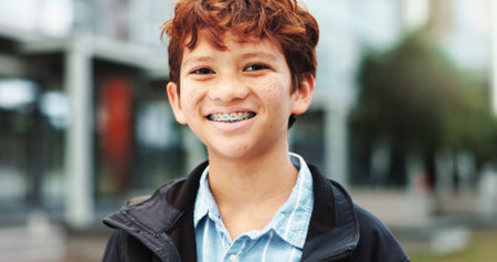 Outdoor, school and boy with smile in portrait, education and studying opportunity with happiness. Campus, male child and student with with confidence for elementary, learning academy and bracesの写真素材