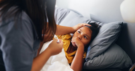 Thermometer, mother and girl in bed, fever and home with illness, cold and monitor disease. Apartment, family and parent with child, mama and sick with care, virus infection and help with concernの写真素材