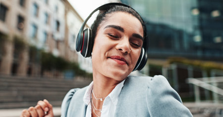 Business, headphones and woman in city, dancing and success with celebration. Person, employee and consultant in workplace, headset and streaming for music, audio and sound with energy and smileの写真素材