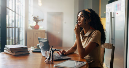 Girl, student and laptop with thinking in kitchen for online course, e learning or problem solving for test. Woman, person and editing project on pc for education, scholarship or research at houseの写真素材