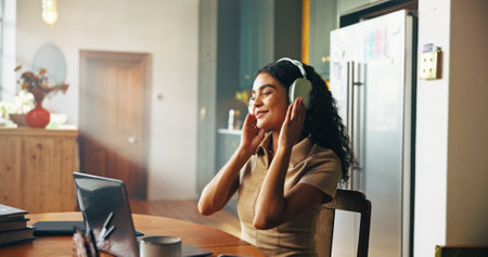 Woman, student and headphones with music in home for break with laptop, happy or online course in morning. Girl, person and e learning with streaming subscription, education or scholarship in kitchenの写真素材