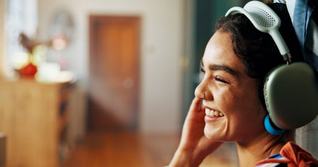 Podcast, headphones and girl laughing in house living room for streaming radio or comedy. Relax, zen and happy woman with smile in lounge listening to funny audio, joke or sound in home for humorの写真素材