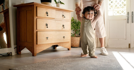 Parent, baby and holding hands for learning to walk with first steps, mobility support or child development. Milestone, person or helping toddler with teaching balance, coordination or growth in homeの写真素材