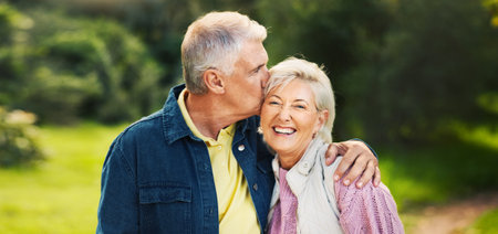 Kiss, happy and old couple in park for support, commitment and relax together outdoors in morning. Retirement, nature and senior man and woman laugh embrace for bonding, relationship or romanceの写真素材