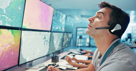 Computer, emergency service and man with headset for global security, dispatcher and operator. Telecommunication, surveillance maps and first responder on monitor for incident report, contact or helpの写真素材
