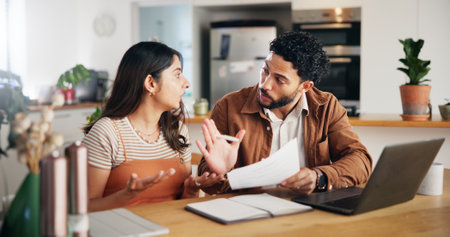 Finance, laptop and couple fight in home with paperwork for argument, budget and stress for debt. Document, man and woman in conflict for bills, tax expenses and bankruptcy crisis with payment failの写真素材