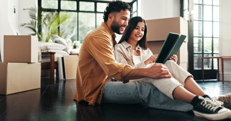 Tablet, reading and couple in new home with planning for renovation. development or moving. Cardboard packages, real estate and man with woman on digital technology for online order in apartment.の写真素材