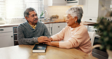 Senior couple, bible and pray with faith in home, holding hands and religion with worship in retirement. Elderly man, woman and support for peace, book and together with praise, gratitude and Godの写真素材