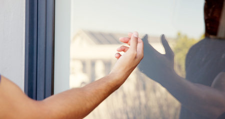 Hand, person and knocking on door of house for entrance, arrival alert and respect for visit of homeowner. Guest, glass and reflection with announcement, attention and waiting for entry permissionの写真素材