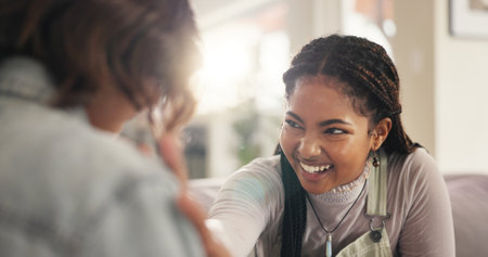 Bonding, joke and smile with women on sofa in living room of home together for reunion or visit. Conversation, laughing and relax with funny friends in apartment for gossip or relationship on weekendの写真素材