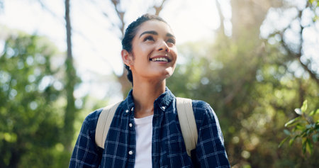 Thinking, hiking and woman with smile, travel and contemplation with fitness, hobby and wonder. Outdoor, hiker and happy person in forest, vacation activity or sightseeing with environment or exploreの写真素材