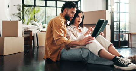 Tablet, cardboard and couple in new home with planning for renovation. development or moving. Boxes, real estate and man with woman on digital technology for online order with maintenance in house.の写真素材