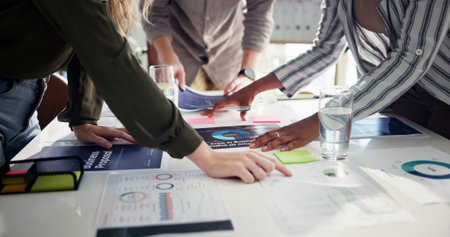 Business people, hands and meeting with documents for statistics, company review or analysis at office. Group, employees or paperwork with data, graph or chart for performance, growth or proposalの写真素材