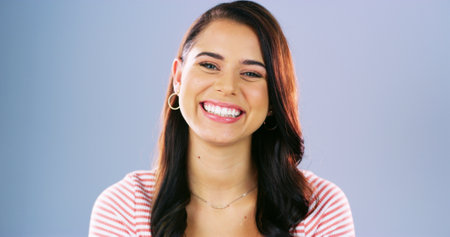Happy, smile and portrait of woman in studio for positive attitude, confidence and pride. Emotions, mockup space and isolated person with joy, good mood and excited expression on blue backgroundの写真素材