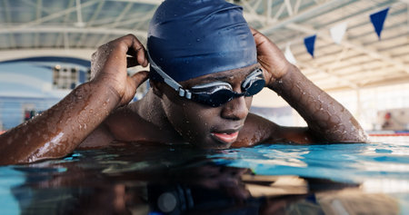 Swimming pool, sports and black man in water for workout, training and exercise for race event. Fitness, aquatic center and swimmer in gym for practice, challenge and competition for performanceの写真素材