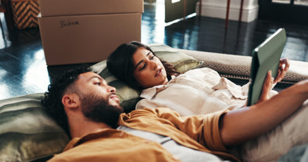 Couple, talk and floor on tablet in new home for relocation, interior design and online shopping. People, planning and discussion for digital app, furniture search and decision for renovation processの写真素材