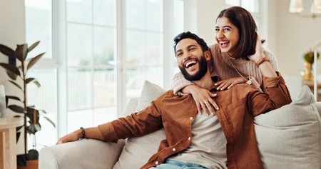 Hug, happy and couple in home, bonding and relax in living room with smile, man and woman on break. Embrace, comfortable and people in relationship on couch, laughing and conversation, chat or houseの写真素材