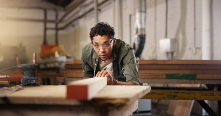 Man, carpenter and beam with workbench at workshop for polish, craft or timber project. Male person,...
