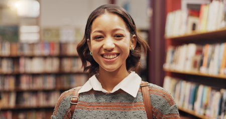Girl, student and portrait with smile at library, excited or education for development with research at college. Person, happy and learning with pride, backpack or scholarship at university in Brazilの写真素材
