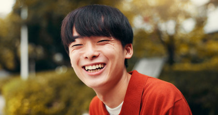Man, portrait and outdoor Japan for laughing, happy tourist and relax on bench in nature for peace. Male person, travel and journey to holiday destination for joke, funny humor and weekend for breakの写真素材