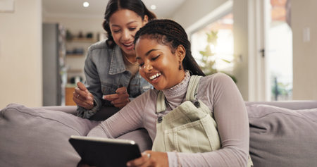 Entertainment, happy and friends with tablet, home and women with smile for movies, living room and relax. House, girls and people with tech for comedy film, laughing or watching on website in loungeの写真素材