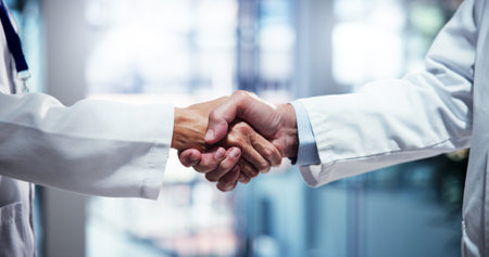 People, scientist or meeting with handshake for partnership, medical agreement or deal at hospital. Closeup, teamwork or health employees shaking hands with greeting for research, b2b or clinic trialの写真素材