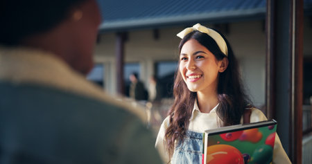 Students, girl and talking in hallway at high school for education break, exam advice and share study tips. Friends, people and book with conversation at campus for scholarship, discussion and chatの写真素材
