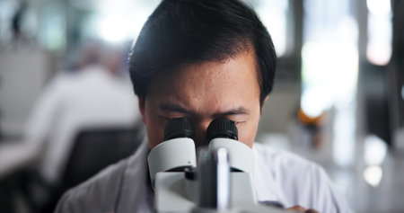 Man, research or scientist with microscope for forensic study or new discovery at laboratory. Male person, medical worker or inspect with lens for micro organism, scientific breakthrough or chemistryの写真素材