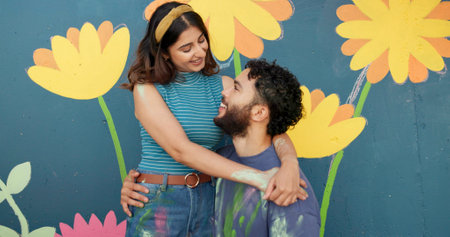 Hug, wall and couple with painting happy for art project, creative design and decoration outdoors. Renovation, smile and man and woman with inspiration for flowers, aesthetic or DIY makeover togetherの写真素材