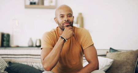 Portrait, relax and thinking with man on sofa in living room of home for ideas, planning or rest. Contemplation, future and vision with confident person in apartment for inspiration or optimismの写真素材