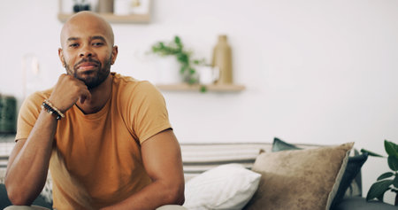 Portrait, space and thinking with man on sofa in living room of home for ideas, planning or rest. Contemplation, future and relax with confident person in apartment for inspiration or optimismの写真素材