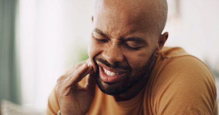 Toothache, pain and man in house with dental problem for cavity, gum disease or gingivitis. Inflammation, dentistry and male person with impacted wisdom teeth for tension, pressure or plaque in home.の写真素材