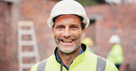 Happy, mature man and portrait of construction worker on site with confidence for property development. Pride, industry and male civil engineer at building for maintenance, repairs or renovation.の写真素材