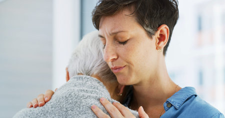 Crying, comfort and woman hugging senior mother in retirement home for grief, support or loss. Sad,...