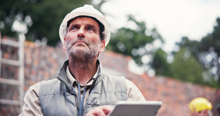 Construction site, man and contractor with tablet, thinking and checklist with inspection. Mature person, architecture and employee idea with hard hat, tech and safety with digital app or real estateの写真素材
