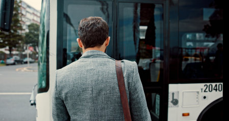 Back, bus stop and business with man, travel and public transport with urban journey. Person, outdoor and passenger with boarding, traffic or schedule with vehicle, delay and city service in New Yorkの写真素材