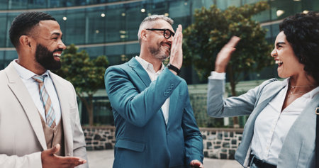 High five, success and happy business people in city for celebration, partnership and agreement. Corporate, professional and men and women for collaboration, support and teamwork in urban townの写真素材