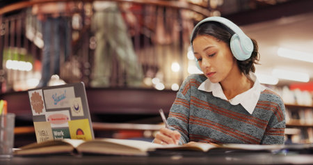 Studying, student and woman with headphones, library and listening to music for project and...