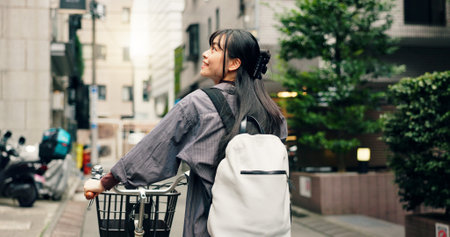 Happy, walking and Asian woman with bicycle in city for commute to university, college and school. Student, cycling and person on bike for travel, sustainability and eco friendly transport in Japanの写真素材