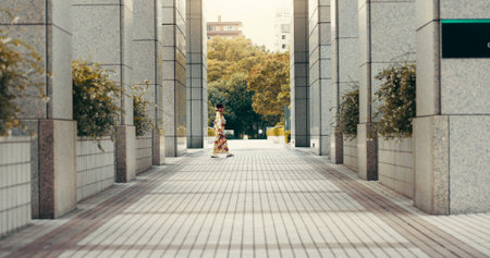 Woman, kimono and walking in city, buildings and travel with profile on urban sidewalk in summer at park. Person, outdoor and traditional fashion with style, clothes and heritage on commute in Japanの写真素材