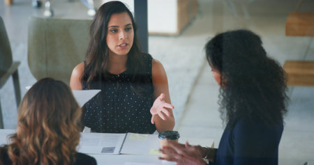 Business people, conversation and women in office, documents and feedback for financial report. Employees, coaching and mentor in workplace, talking and meeting for project development and adviceの写真素材