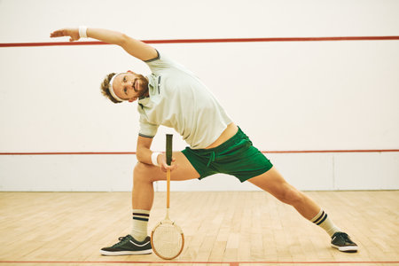 Squash court, stretching and man with fitness, playing and competitive with workout, training and hobby. Person, player and professional athlete with racket, routine and practice for game and cardioの写真素材