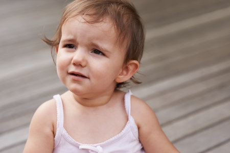 Baby, girl and unhappy or sad outside on porch, stress and upset for mistake or fail in childhood. Kid, toddler and frustration and distress for information, outdoors and autism or attitude on deckの写真素材