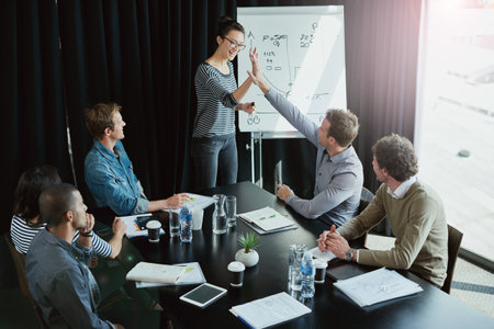 Team, presentation and high five in boardroom for meeting, business planning and white board demonstration. Presenter, company and goal or idea with strategy, collaboration or professional projectの写真素材