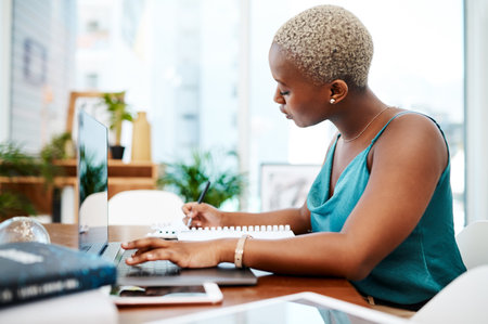 Business, document and black woman writing at laptop for proposal, project review or budget plan. Professional, media agency and female employee for company report, startup or online in officeの写真素材
