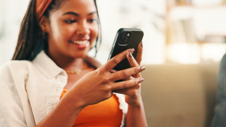 Smile, hands and woman with mobile in home for social media, reading forum and ebook. Person, smartphone and relax on sofa with chat app for communication, text notification or download game onlineの写真素材