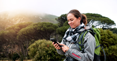 Hiking, phone and scroll with woman in nature for social media post, travel and adventure. Communication app, trekking and environment with person outdoor for eco tourism, backpacking and vacationの写真素材