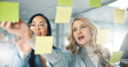 Team, glass and business women with sticky notes for brainstorming project ideas, schedule and...