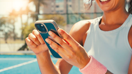 Tennis, hands and woman on court with mobile, social media or scroll on training app for exercise tips. Athlete, smile or phone on sports ground for blog update, fitness research or club registrationの写真素材