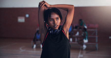 Basketball, fitness and girl with stretching on court for match preparation, tournament exercise and thinking. Workout, player and arm warm up for game performance, sport practice and getting readyの写真素材